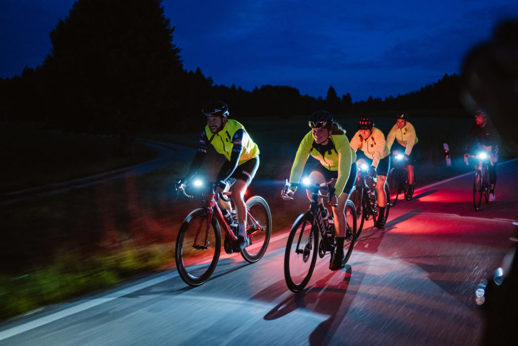 Cyclists riding their bike through the darkness.